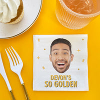 Custom Napkin with a printed face and 'Devon's So Golden' text on a yellow table with a dessert and drink. Golden Birthday Party