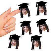 A hand holding a set of custom photo stickers of a person wearing a graduation cap.