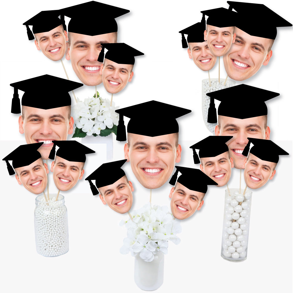 A collection of customized graduation photo head cutouts on sticks, showing various individuals wearing graduation caps. Graduation head on a stick
