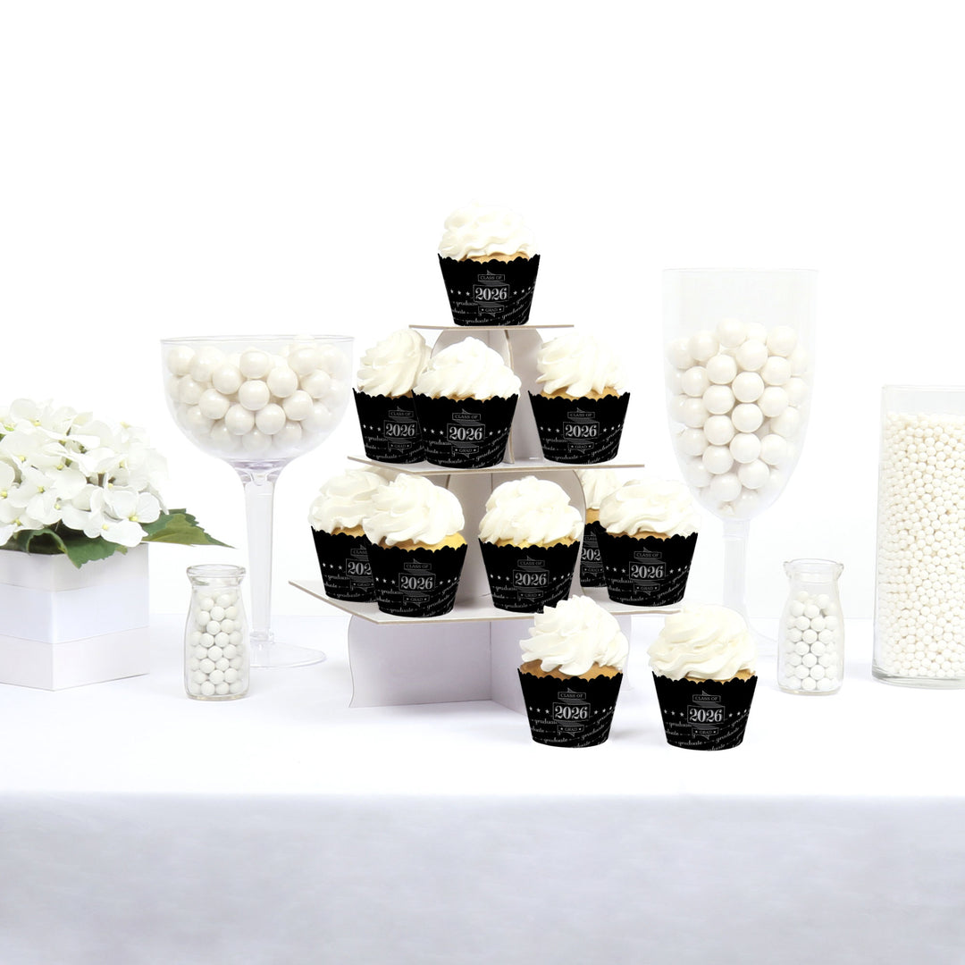 Cupcakes in black and gold wrappers on a white table with decorative elements.