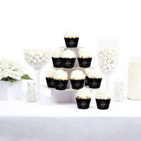 Cupcakes in black and gold wrappers on a white table with decorative elements.