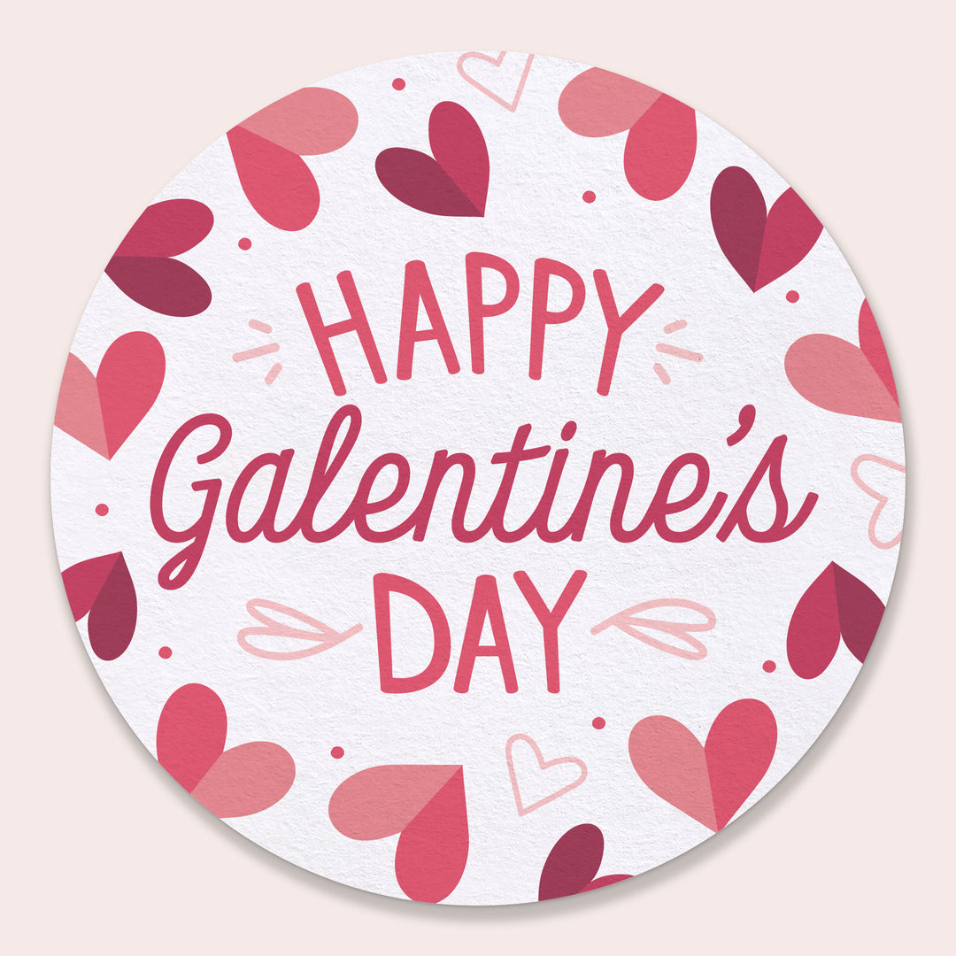Round drink Coaster with 'Happy Galentine's Day' text and heart designs on a light pink background