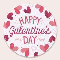 Round drink Coaster with 'Happy Galentine's Day' text and heart designs on a light pink background