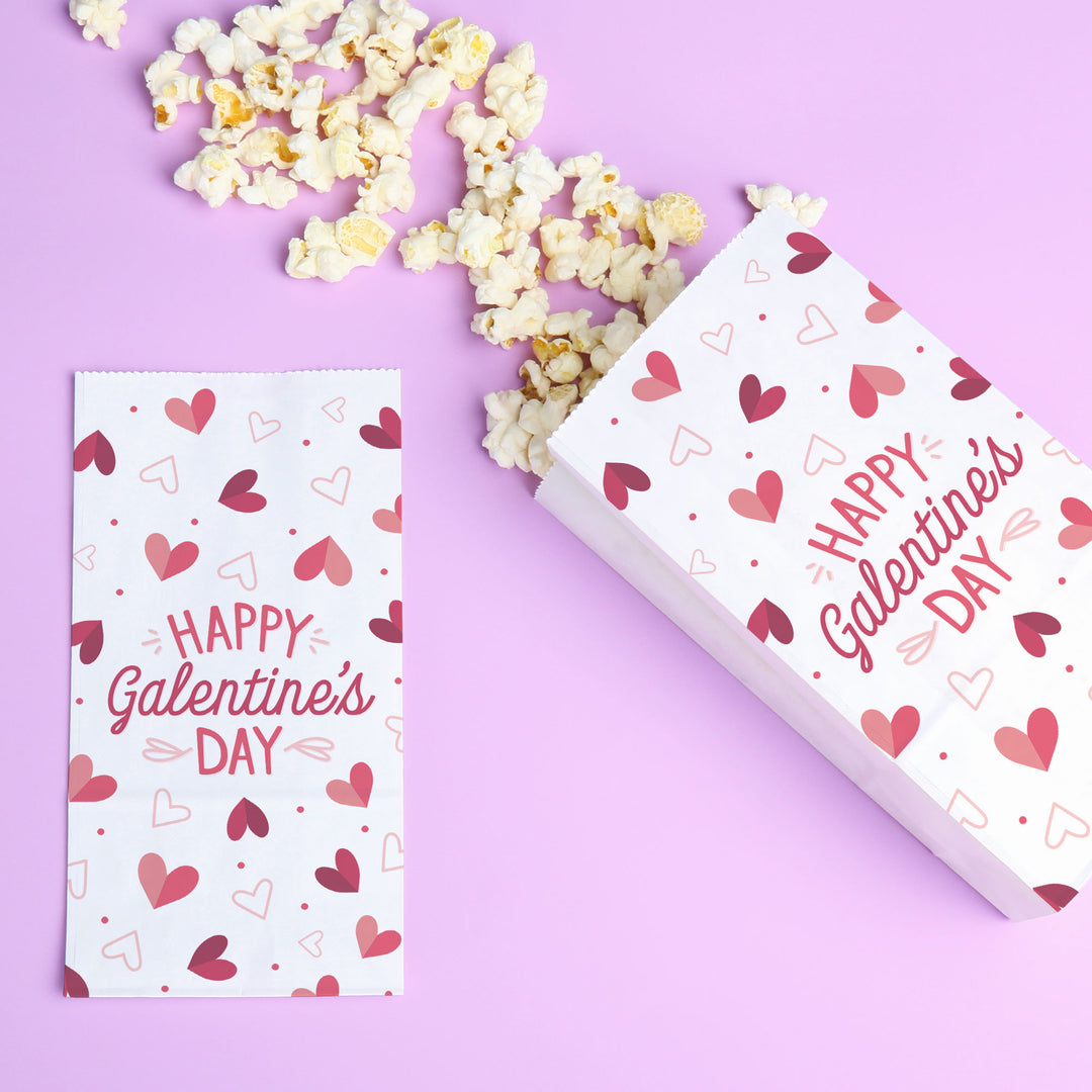 Two boxes with 'Happy Galentine's Day' text and heart patterns on a purple background with popcorn.