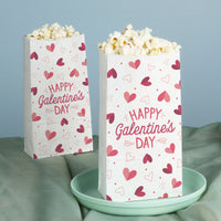 Two popcorn bags with 'Happy Valentine's Day' text and heart patterns on a light blue background.