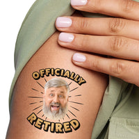 A close-up image of a person's arm with a custom temporary tattoo that has the phrase 'OFFICIALLY RETIRED' tattoo and a photo of a smiling person's face.