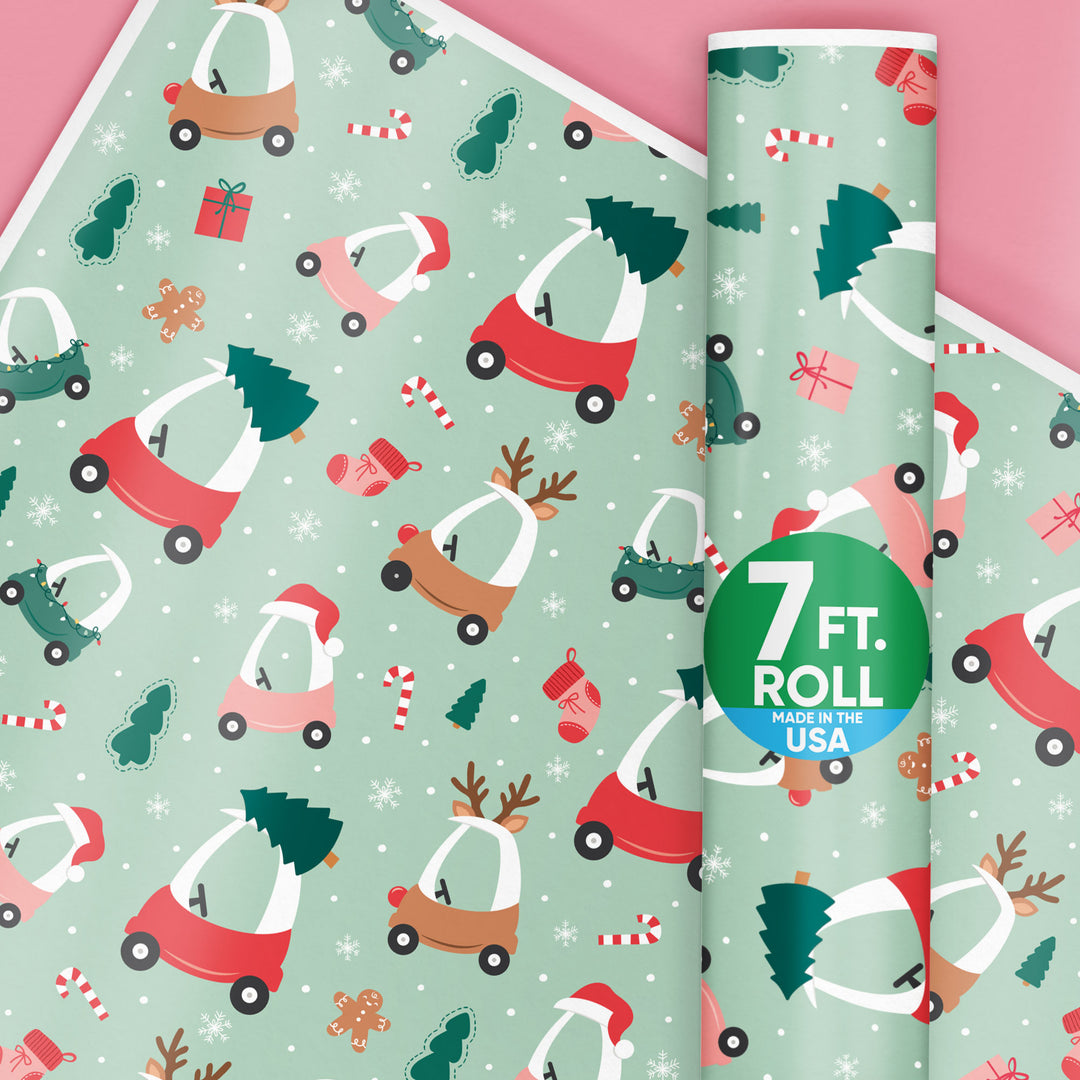 Christmas-themed wrapping paper with small vehicles and trees on a light green background, featuring a roll of paper.