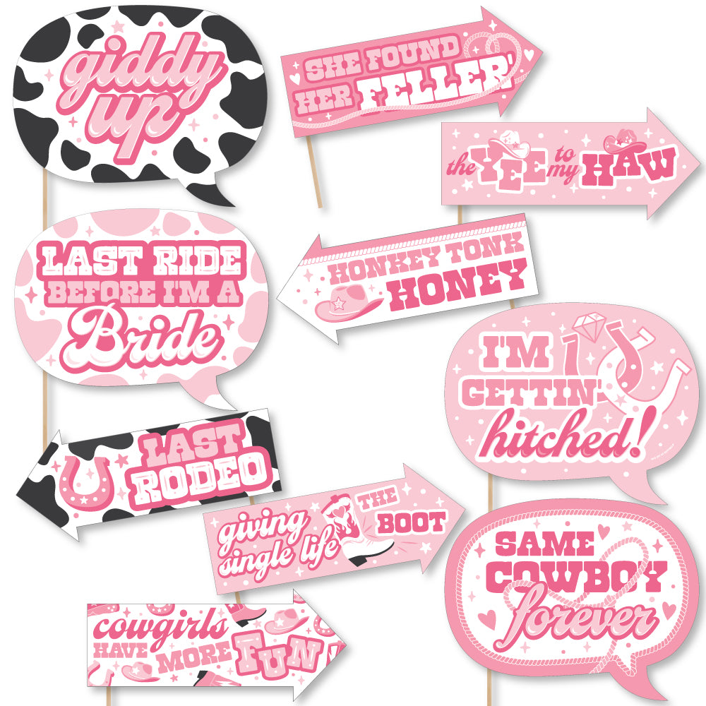 A collection of pink and black photo booth props with humorous text related to a bachelorette party, including phrases like 'Last Rodeo' and 'Giddy Up'.