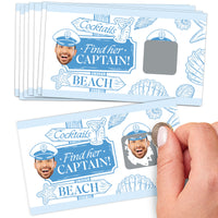 A hand holding a scratch-off card game with a beach and cocktails theme, titled 'Find her Captain!'. The card shows a face hidden under a scratch-off layer and is labeled with 'Cocktails' and 'Beach'.