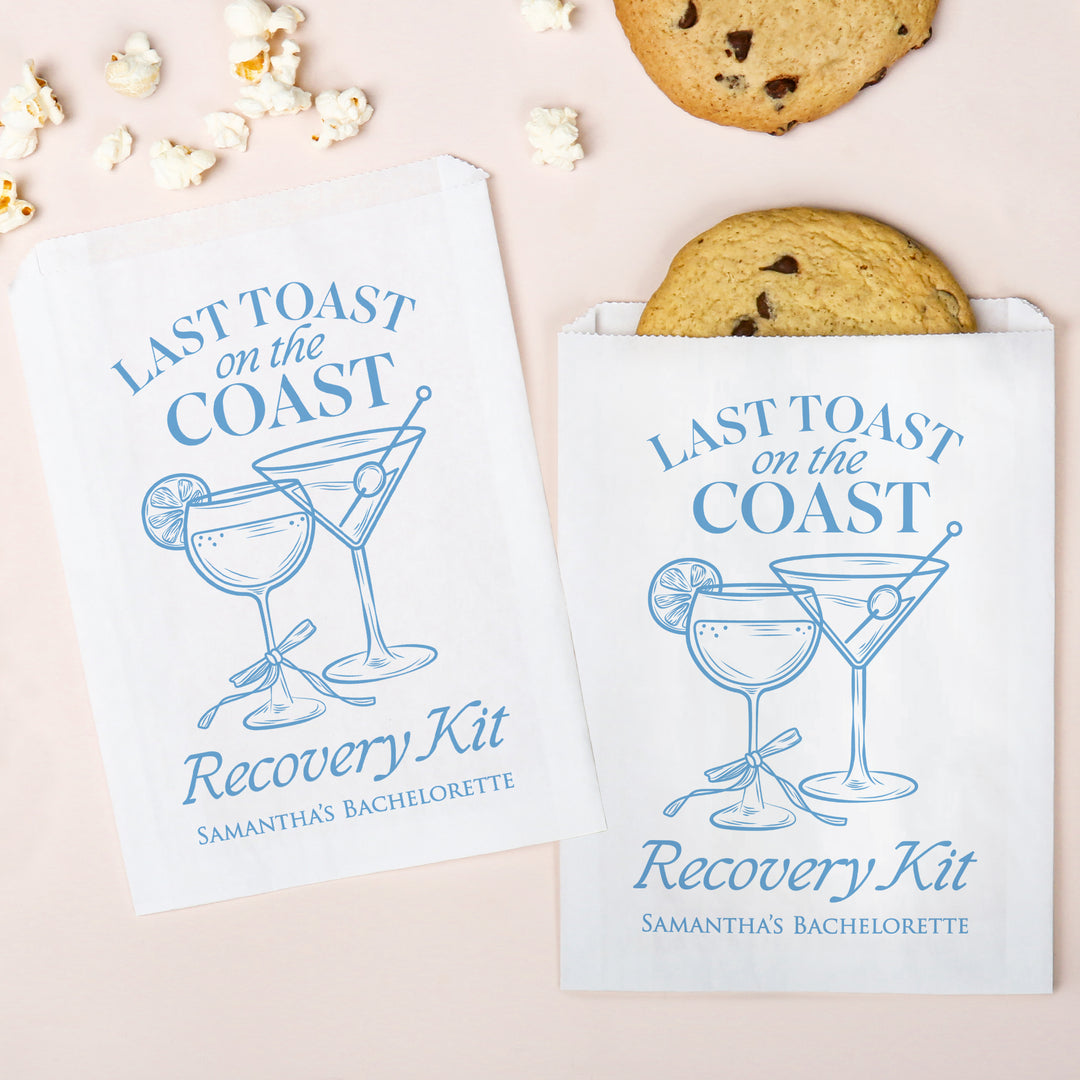 Two 'Last Toast on the Coast Recovery Kit' packages with cookies and popcorn on a light pink background.