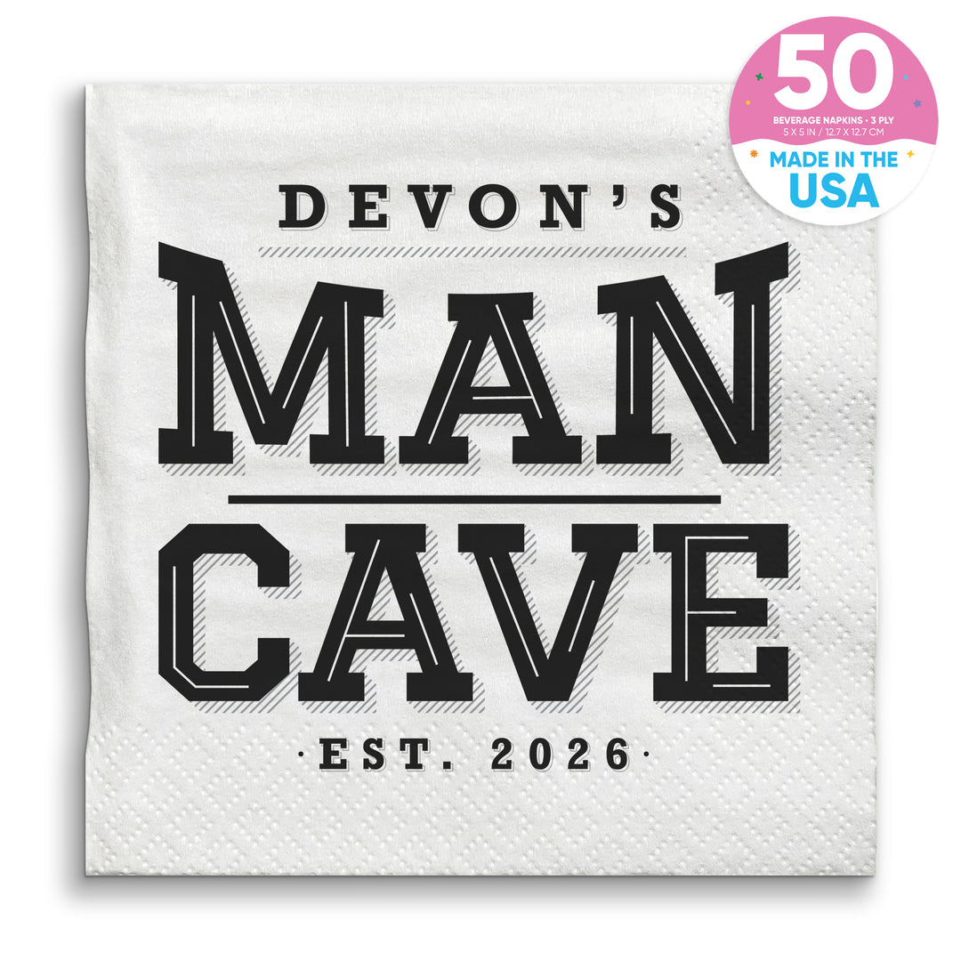 A white paper napkin with 'DEVON'S MAN CAVE EST. 2026' printed in black text.