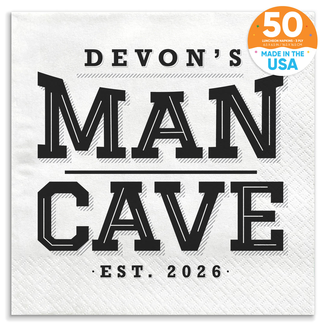 A white paper napkin with 'DEVON'S MAN CAVE EST. 2026' printed in black text.