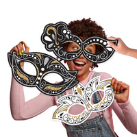 A person holding up three large, decorative masks in black, white, and black with gold accents, designed for use as photo props.
