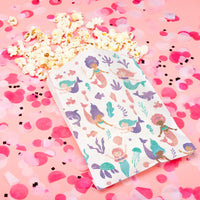 Sheet of mermaid stickers on a pink background with popcorn