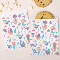 Two cookie wraps with mermaid pattern on a pink background with cookies and popcorn.