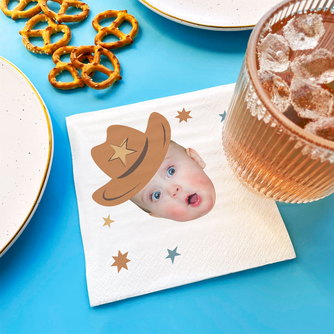 Custom Napkin with a child wearing a cowboy hat on a blue surface with pretzels and a glass of iced tea.