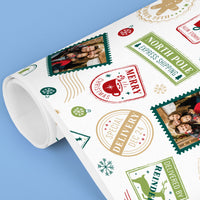 Roll of Christmas-themed wrapping paper with stamps and photos on a blue background