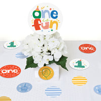 Decorative table centerpieces with 'one is fun' birthday table confetti and white flowers on a white background.