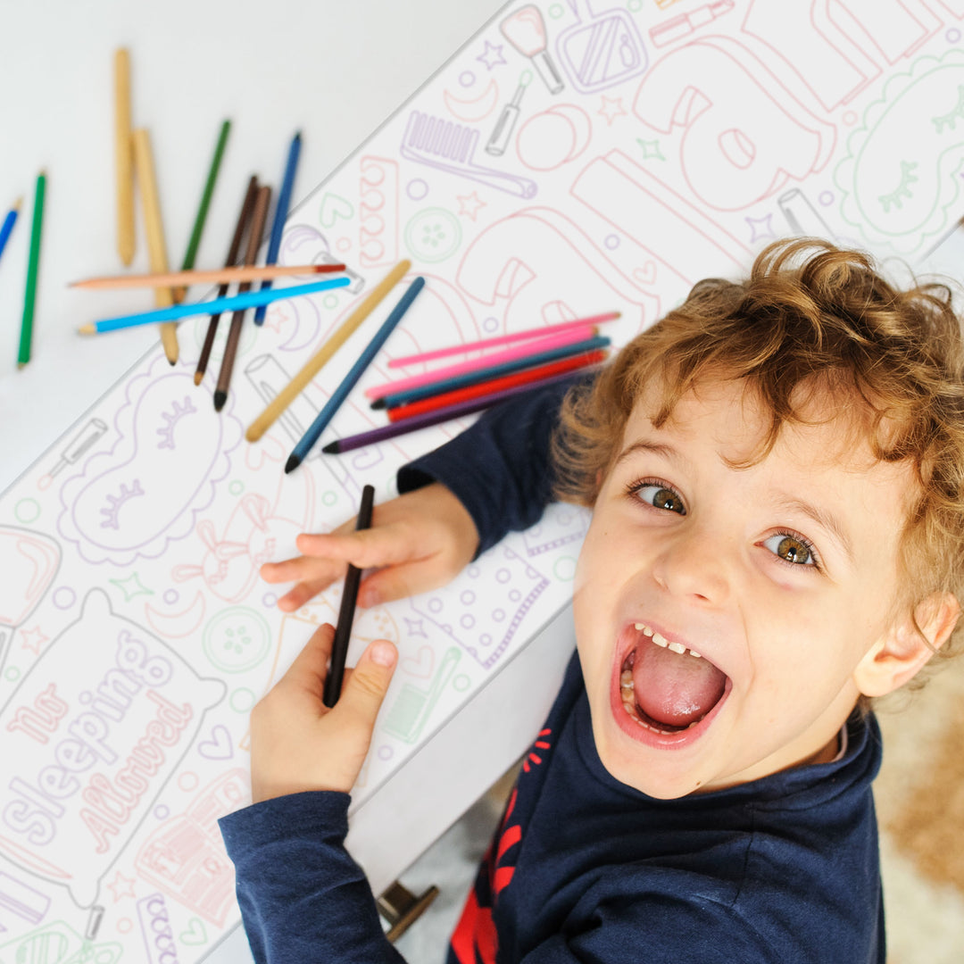 Child coloring with crayons on a sheet of paper with various sleep over shapes and designs.