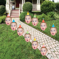 A set of 10 custom photo party yard signs displayed on a lawn, featuring cut-outs of a person's face with party hats.