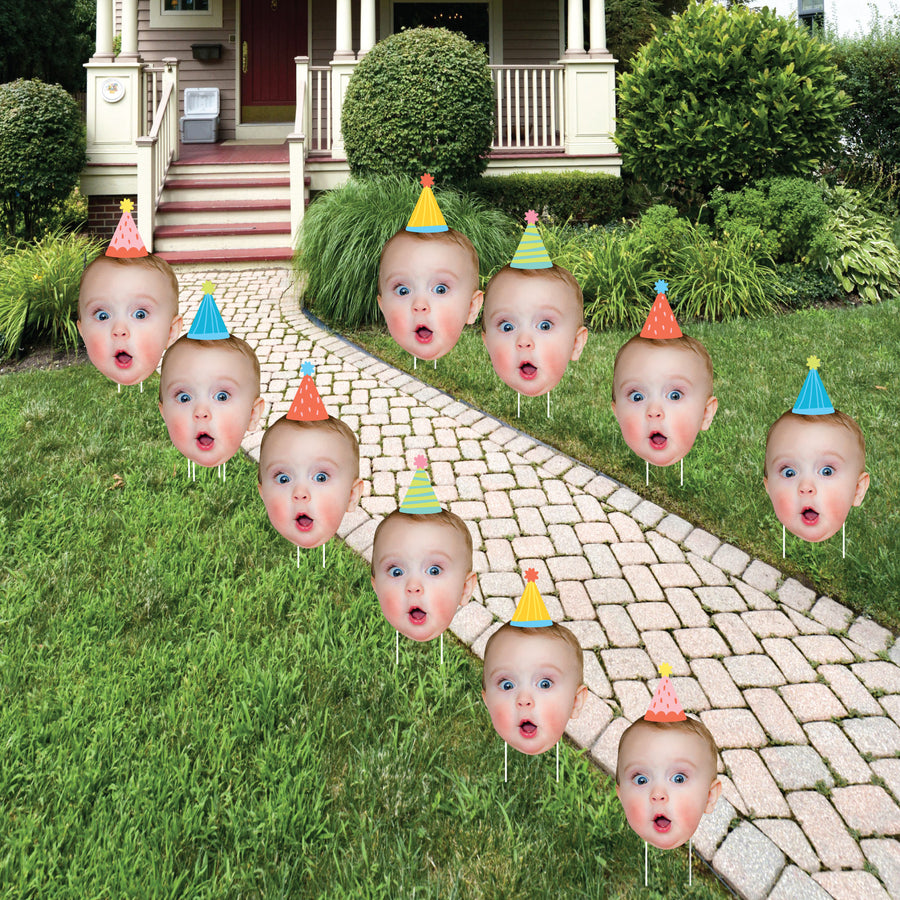 A set of 10 custom photo party yard signs displayed on a lawn, featuring cut-outs of a person's face with party hats.