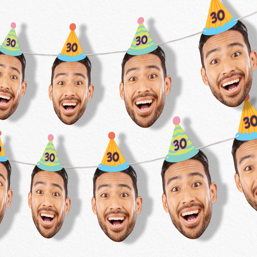 A series of custom oversized face cutouts with a man smiling, wearing colorful birthday hats with the number 30 on them, strung together with white satin cording.