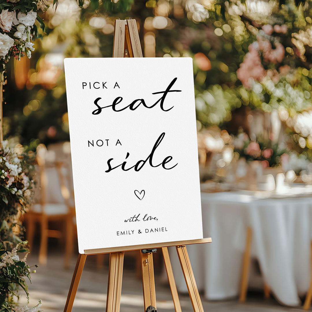 Wedding sign on an easel with floral decorations and tables in the background