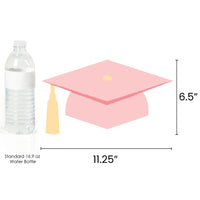 Paper graduation cap with tassel next to a water bottle for size comparison on a white background