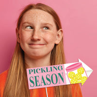 Person with a 'Pickingling Season' sign on a pink background for girl pickleball party 