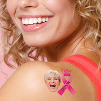 Woman with a custom temporary tattoo of a smiling woman and a pink ribbon on her shoulder.