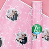 Pink wrapping paper with snowflake pattern and family photo, featuring a 7 ft. roll label.