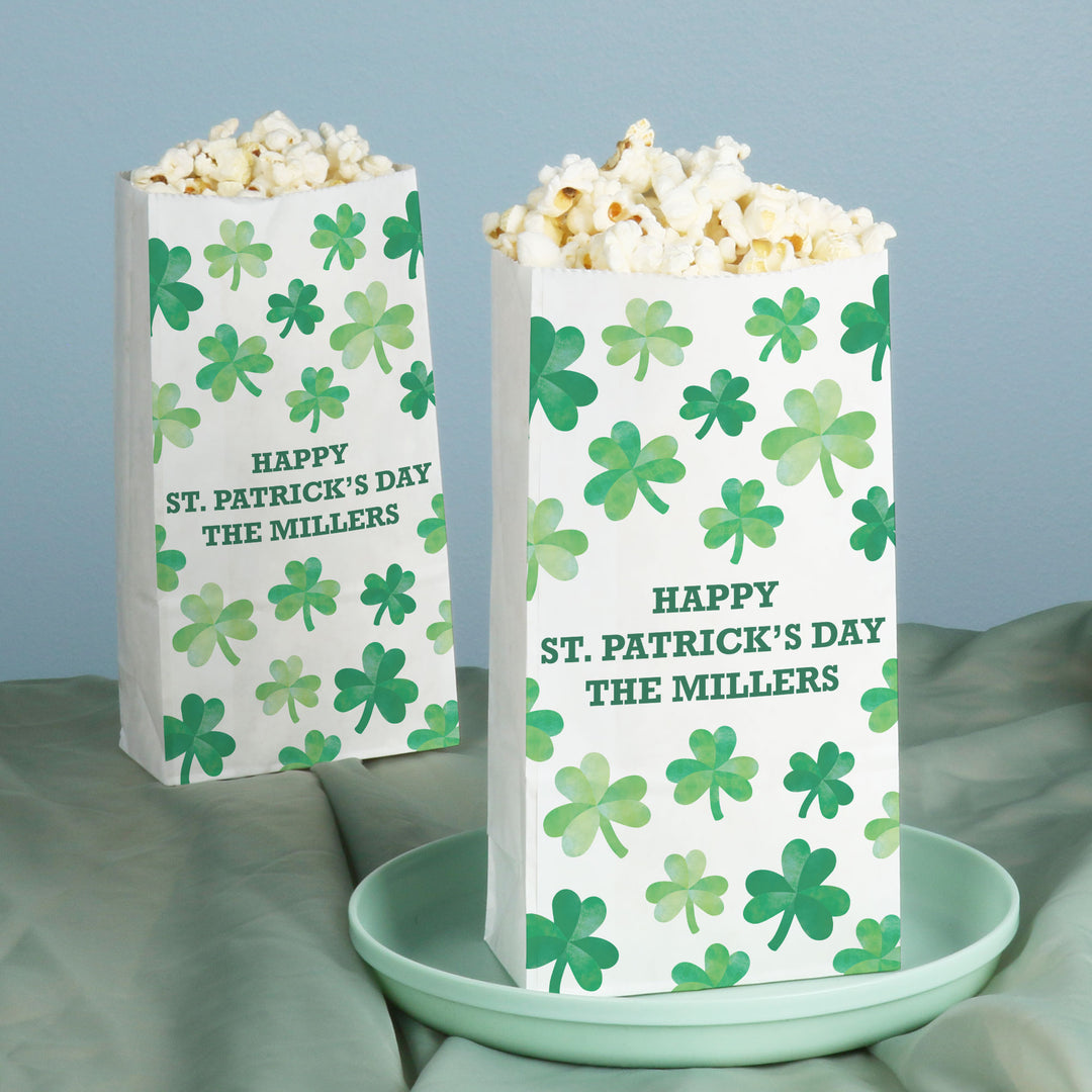 Two popcorn bags with shamrock pattern and 'Happy St. Patrick's Day' text on a light blue background.