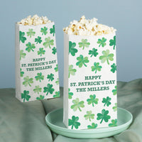 Two popcorn bags with shamrock pattern and 'Happy St. Patrick's Day' text on a light blue background.