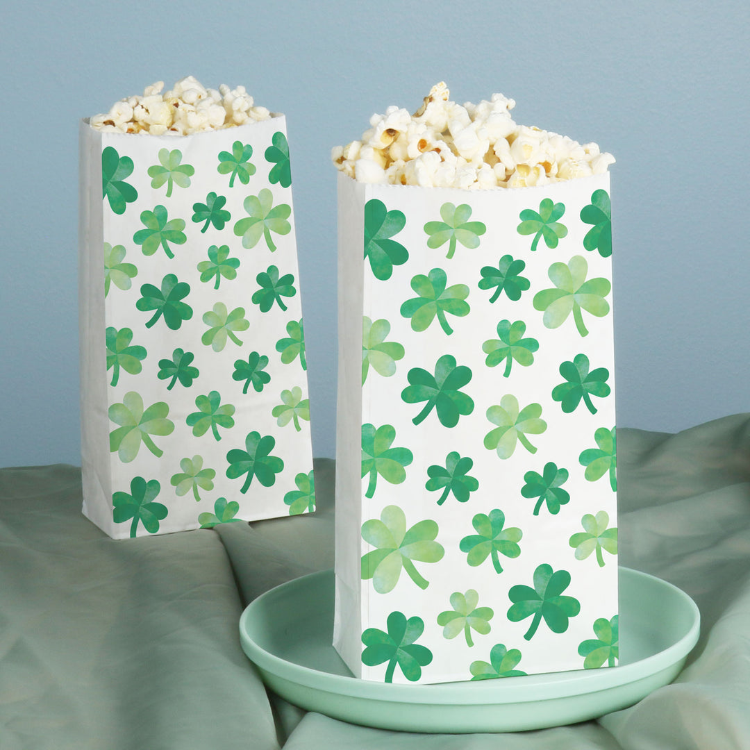 Two popcorn bags with green shamrock pattern on a light blue background