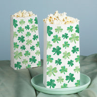 Two popcorn bags with green shamrock pattern on a light blue background