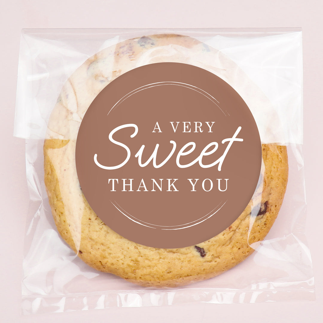Cookie in clear packaging with a brown label saying 'A Very Sweet Thank You' on a light pink background