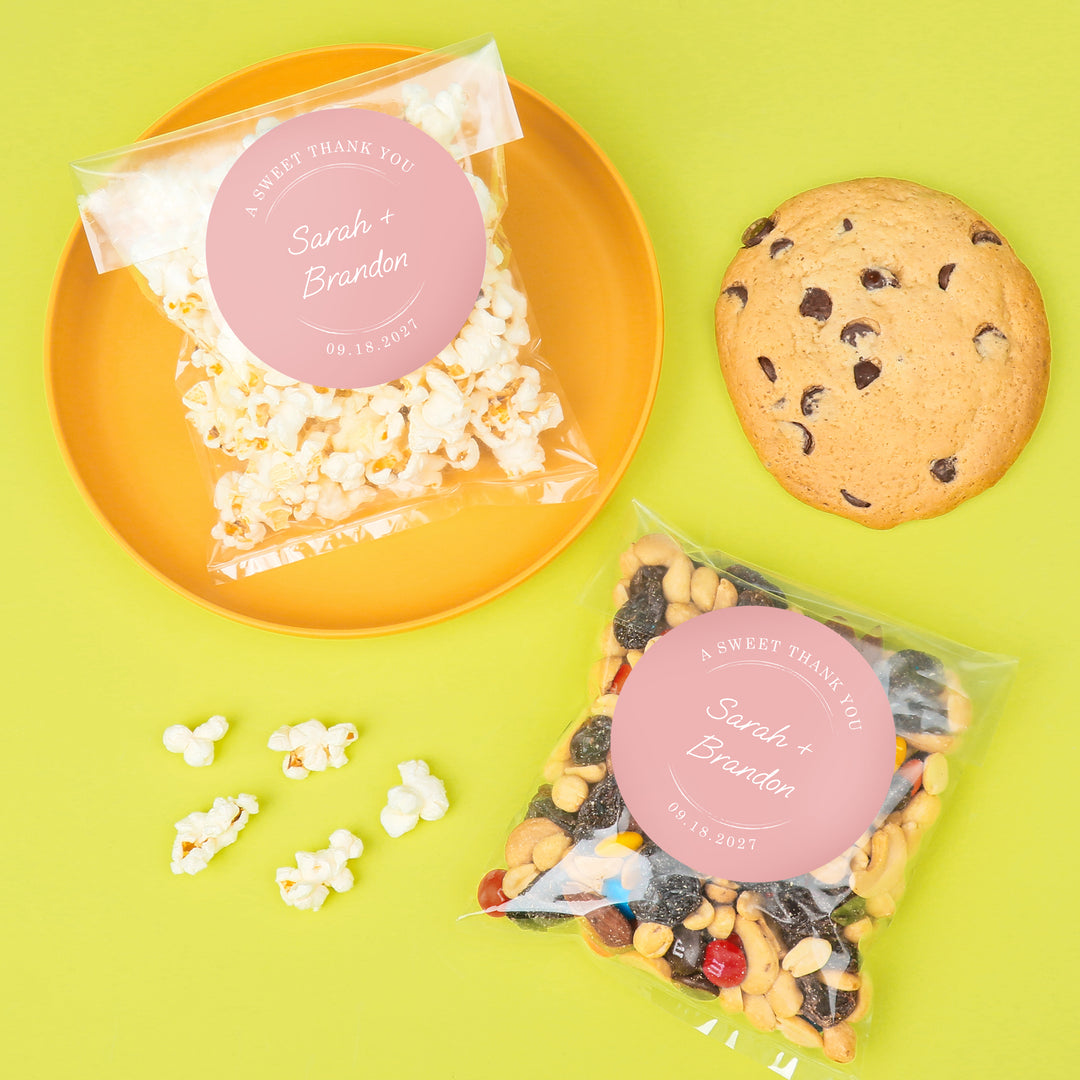 Snack bags with personalized labels, popcorn, cookies, and trail mix on a green background