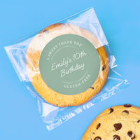 Chocolate chip cookie with a personalized wedding favor label on a blue background