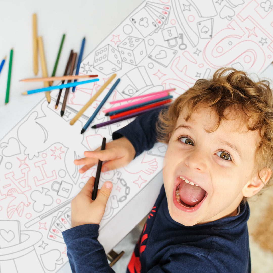 Child coloring with crayons on a Magic themed doodles coloring table runner top hats and cards