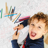 Child coloring with crayons on a Magic themed doodles coloring table runner top hats and cards