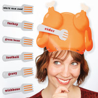 A person wearing an orange turkey-shaped hat with paper forks attached to it, each fork having a written prompt. The image depicts the fun Thanksgiving Turkey Guessing Game, where players use forks with prompts to guess who they are.