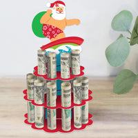 A graphic image of a red and green DIY beach Santa holiday party money holder gift shaped like a cake with rolled-up bills in each slot and a cartoon of Santa Claus surfboarding on top.