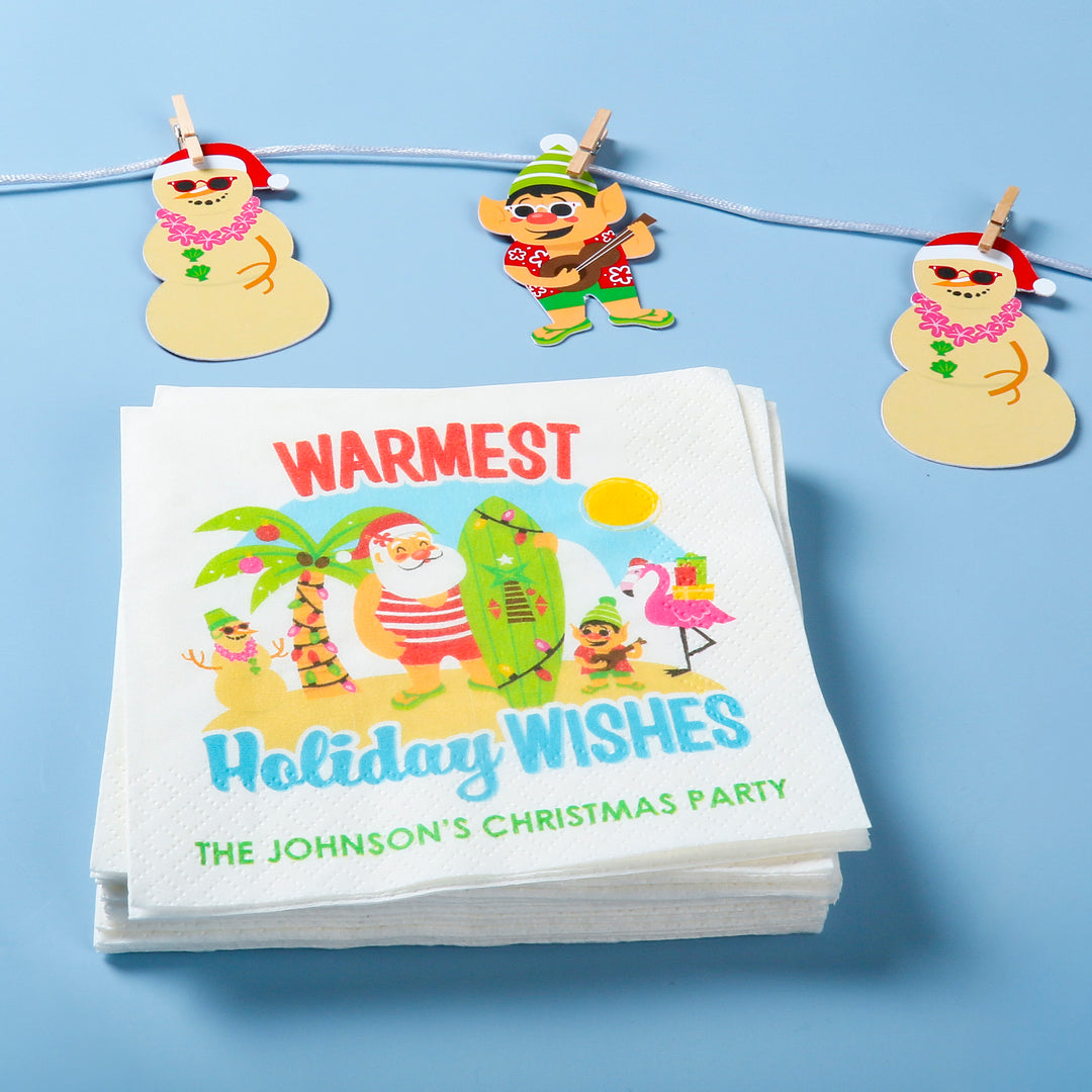 Stack of Christmas-themed napkins with cartoon elf on beach characters on a blue background