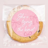 Cookie with a pink label reading 'She's tying the knot' on a light pink background
