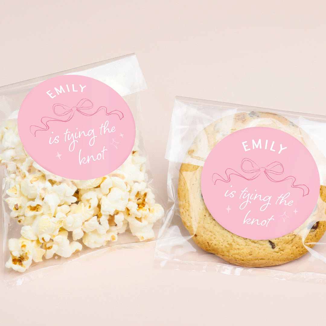 Popcorn and cookie packages with 'EMILY is tying the knot' labels on a beige background