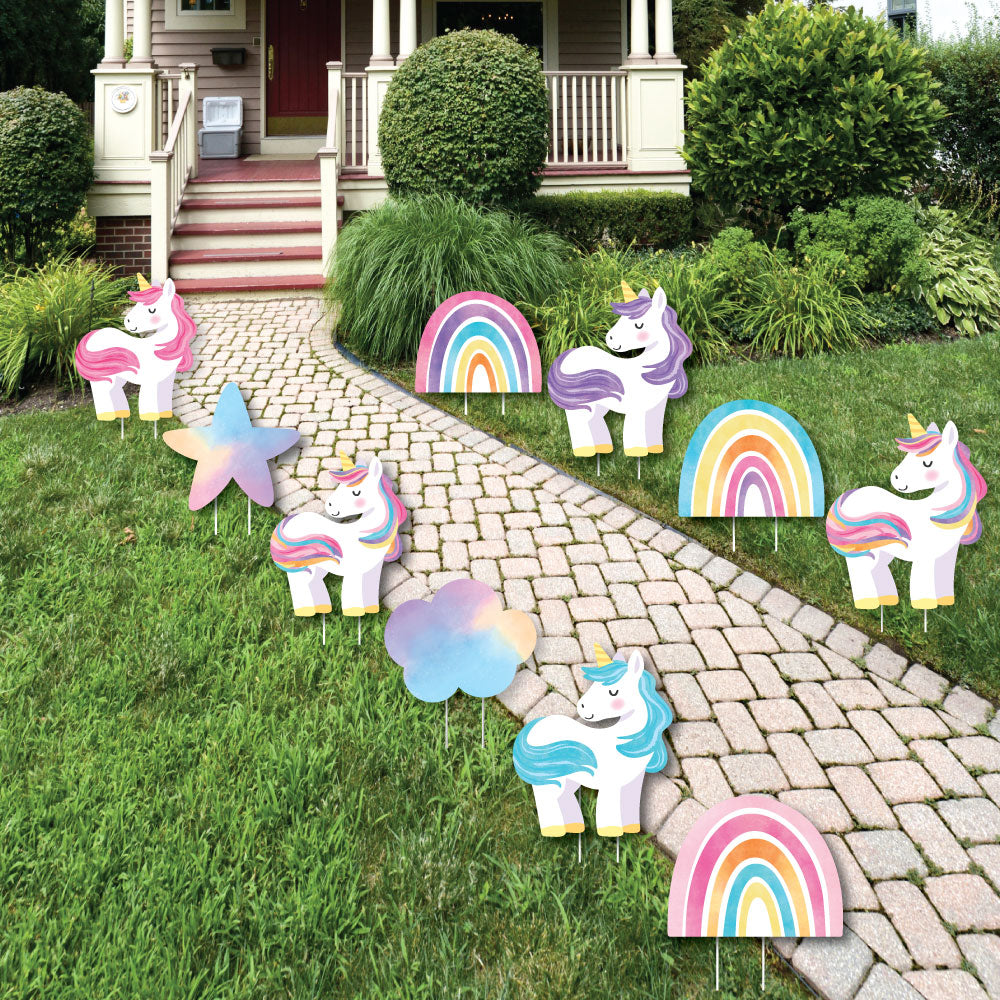 Unicorn and rainbow yard decorations on a grassy lawn with a house in the background.