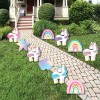 Unicorn and rainbow yard decorations on a grassy lawn with a house in the background.