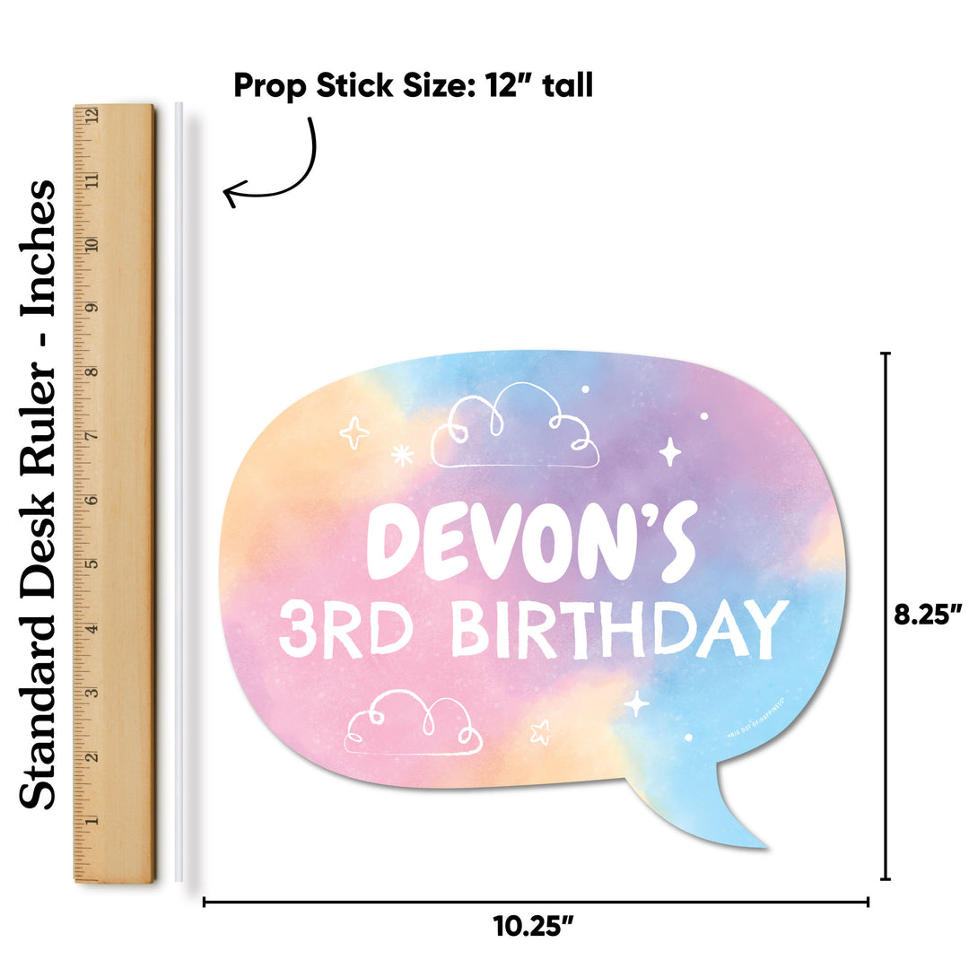 Colorful rainbow watercolor prop stick with 'Devon's 3rd Birthday' text, next to a ruler for size reference.