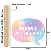 Colorful rainbow watercolor prop stick with 'Devon's 3rd Birthday' text, next to a ruler for size reference.