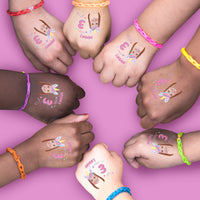 Children's hands with custom unicorn temporary tattoos and colorful bracelets on a pink background